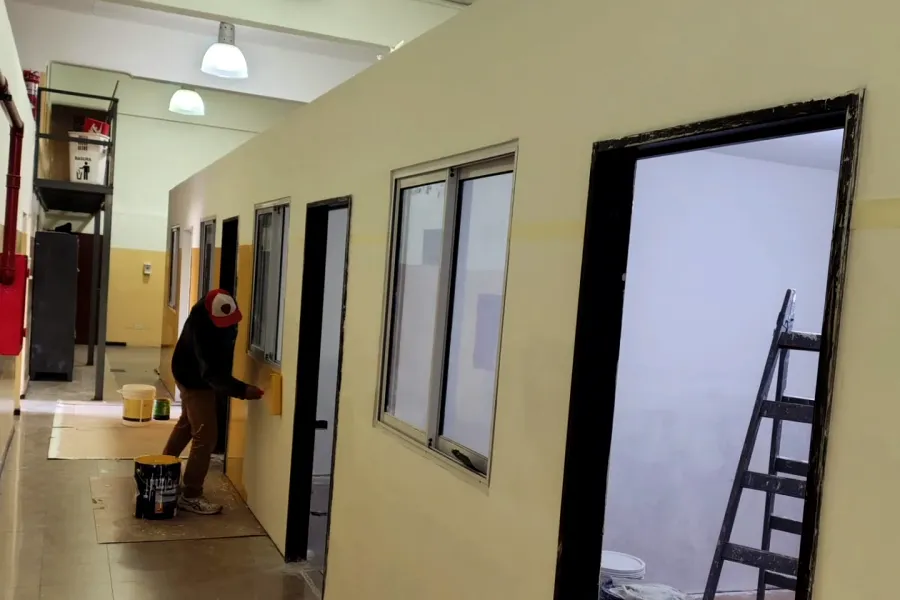 Trabajo real en obra: pared de drywall terminada, con aberturas colocadas y una persona pintando.