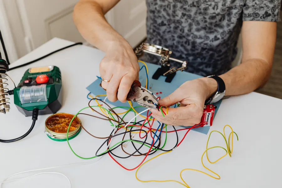 Imagen ilustrativa: manos preparando cables con una pinza.