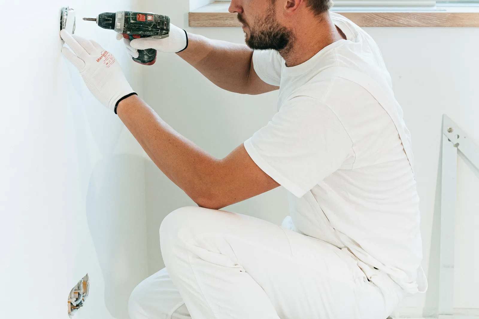 Imagen ilustrativa: persona instalando una caja de tomacorriente en la pared de una casa.