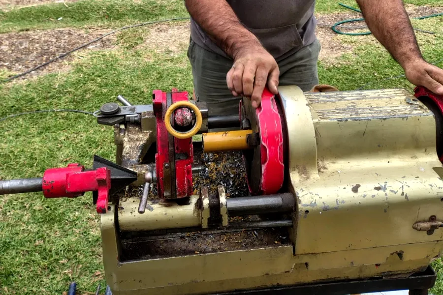 Trabajo real en obra: manos roscando un caño con una roscadora.